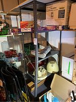 Photo of a metal storage shelving unit holding various household items including craft supplies, decorative items, and small boxes.