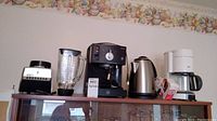 Full lot view showing all four kitchen appliances on a wooden shelf against a floral wallpaper border.