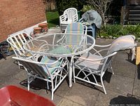 Full view photo of the outdoor dining set with one rectangular table and four chairs arranged around it on a patio.