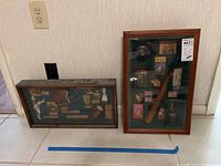 Two framed sports memorabilia collages leaning against the wall by an electrical outlet.