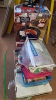 Photo showing boxed snowman platter and bowl serving set atop a stack of various Christmas decorations and items in plastic containers.