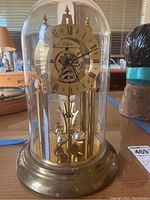 Front view of the Elgin brass domed anniversary clock in its glass cover showing entire clock and dial.
