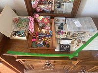 Wide view of all jewelry on wooden dressers including necklaces, earrings, and plastic box