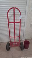 Full view of red Milwaukee steel hand truck showing the handle, frame, and wheels.