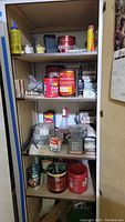 Shelf with various hardware items including glue cans, screws, and other supplies