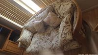 Full view of the love seat sofa showing wood frame and leafy patterned cushions in beige and brown.