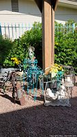 Photo showing overall outdoor lot with plant stands, yard statues, pump handle, wind chimes