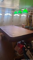 Pool table with cover in a garage setting under green hanging lights.