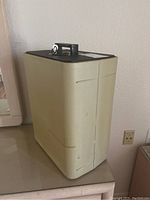 Front side view of the beige safe with black top, mounted key lock and key on top, measuring approximately 8x13x16 inches.