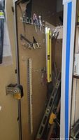 Photo of levels and yardsticks hanging on pegboard and some hand tools on bottom left