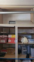 Shelves with various electronics and other items including a beige Coby AM/FM/TV receiver and some boxes