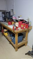 Full side view of the wood framed workbench with attached red 1035 vise and bench grinder on top. Various tools and containers stored on lower shelves and tabletop.