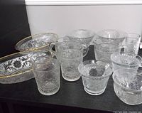 View of all 17 pieces including various bowls and glasses, all clear etched glass with floral decoration.
