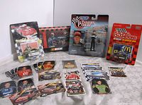Full lot view showing assorted NASCAR die-cast cars, trading cards, and an action figure in original packaging