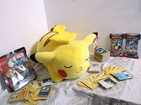 Pikachu plush, two sealed card packs, stacks of loose cards arranged on cloth surface