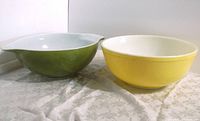 Green 4 quart Pyrex bowl with handle and pouring spout next to yellow Pyrex bowl