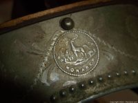 Close-up photo of the embossed Monarch logo on the metal stereoscope viewer showing a deer and other animals with the text 'Monarch'.