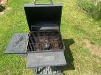 Open Nexgrill charcoal grill showing interior, grates, and side shelves