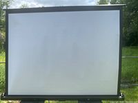 Da-Lite 4'x5' portable projection screen set up showing flat white screen surface with black border outdoors.