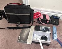 Lot of Samsung Galaxy camera, four camera cases, Zeikos small tripod, and accessories arranged on floor.
