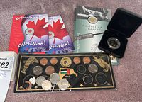 Overview of all coins including Canadian Celebration coins, UAE 24-piece coin set, Australian Legends boxed coin, and loose coins on display board.