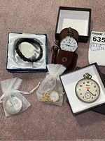 Group image showing four pocket watches and black elastic bracelet with stones in boxes and pouches on carpet.