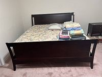 View of the footboard of the king size bed frame showing the dark wood finish and simple rectangular design, with mattress and bedding placed on top not included.