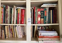 Cookbooks on shelves, showing a variety from older to newer editions and different culinary focuses including baking and vegetarian cooking