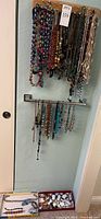 Photo of necklaces hanging on wall racks, showing diverse styles and colors of beads and chains.