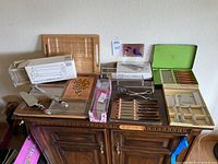 Overview photo of all cutlery sets, serving trays, and boards on wooden cabinet.