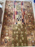 Full view of handmade area rug with geometric and abstract patterns in earth tones and multiple colors.
