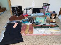 Overview of the lot showing various shapewear garments, pantyhose, self-care items, and electrical accessories spread out on a surface.