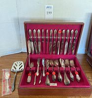 Full overview of 54 pc flatware set in wooden case with red felt lining showing all utensils.
