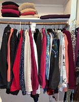 Rack of assorted women's tops, sweaters, and jackets in various colors and styles