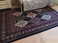 Photo showing the full area rug under a bed with clear view of the geometric and floral patterns, and the fringed edges.