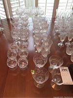Crystal stemware arranged on wooden table, multiple wine and cocktail glasses in rows showing clear crystal cut designs