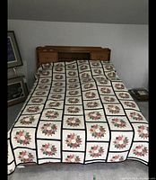 Full bed quilt laid over bed showing entire floral patchwork design with navy blue sashing.
