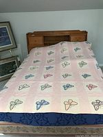 Full view of the quilt spread on bed showing butterfly pattern across pink and white patchwork squares.