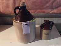 Two stoneware jugs side by side, larger jug has cork and Foley & Co. Potters label.