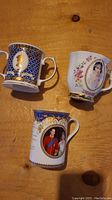 Overview of three commemorative royal mugs with different royalty portraits and decorative gold details