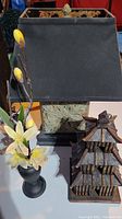 Photo showing the floral arrangement in a black vase, the pagoda-style decorative wooden structure, and the Asian motif lamp with black fabric shade