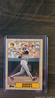 1986 Topps Barry Bonds rookie card in plastic protective sleeve showing front image of Bonds batting for Pittsburgh Pirates with card text and logo.