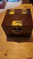 Top view of the closed wooden box showing the brass hinges and latch with a fish design.