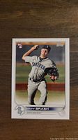 Photo shows a Matt Brash rookie baseball card in a Topps design, picture taken on a wooden surface.