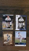 Front view of 4 Mickey Mantle baseball cards laid out on a wooden surface including Upper Deck and Gypsy Queen designs