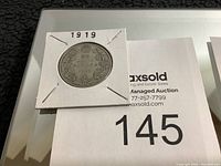 1919 Canadian half dollar coin in a white cardboard holder, showing front with intricate maple leaf design and denomination.