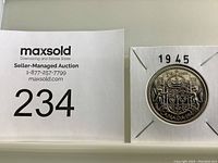 Photo showing the 1945 Canadian half dollar coin secured in a protective holder with lot number displayed alongside for identification.