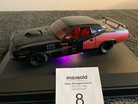 Black and orange 1:18 scale Dodge Charger model car on a display platform, showing closed position with visible red interior through windows.
