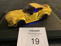 Yellow LEGO sports car displayed on black surface, showing side and front details with seller info card visible.