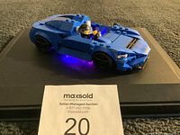 Blue Lego sports car with minifigure and undercarriage blue LED lights displayed on flat surface.